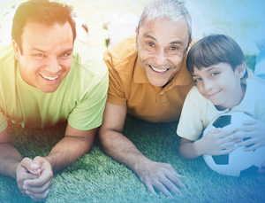 Hispanic grandfather, father and son laying in grass